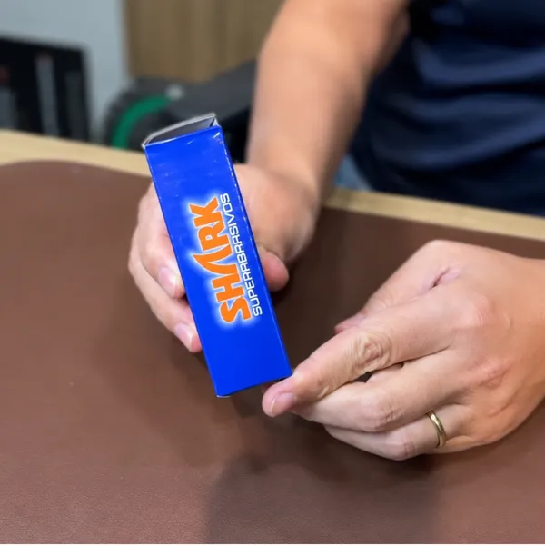 Embalagem azul de produto Shark Superabrasivos sendo apresentada